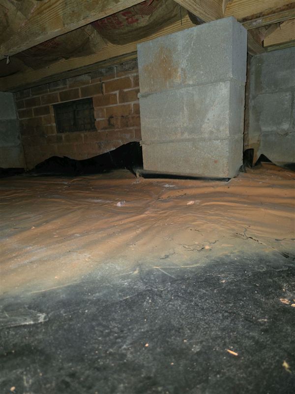 Support piers standing on a plastic vapor barrier in a home's crawlspace